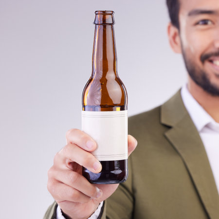 Man face with beer bottle isolated on a white background for alcohol product promotion drink, happy hour and cheers. Professional Asian person or model hand holding wine glass container in studioの写真素材