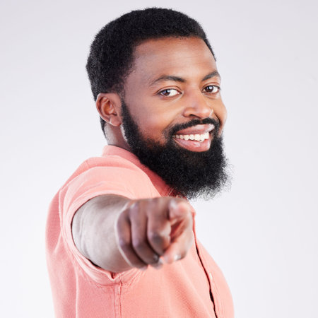 Point, smile and portrait of black man in studio with hand gesture for motivation, encouragement and selection. Happy, mockup and male on white background pointing for choice, advertising or decisionの写真素材