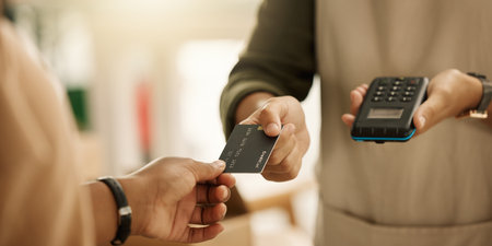 Closeup of hands of a customer paying with a credit card. Entrepreneur accepting payment using a NFC machine. Zoom into hands of a customer making contactless payment using a debit card.の写真素材