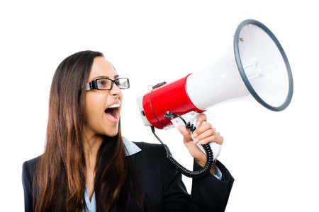 Shouting for the world to hear. a young businesswoman shouting into a megaphone against a studio background.の写真素材