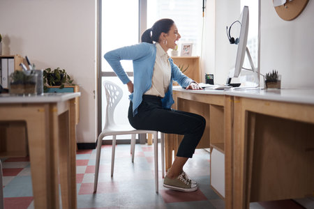 Your body is telling you something. a young businesswoman experiencing back pain while working at...
