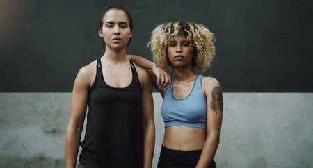 Becoming stronger, fiercer and more powerful. Portrait two sporty young women standing together in a gym.の写真素材