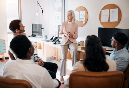 Any questions. a mature businesswoman sitting and training her team in the office.の写真素材