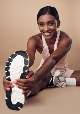 Im ready to get my train on. an attractive young woman sitting alone in the studio and stretching before working out.の写真素材