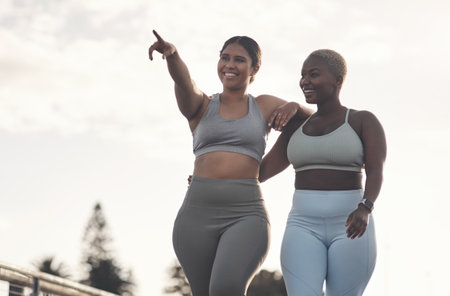 Lets do an uphill race. two young women looking at something while out for a workout together.の写真素材
