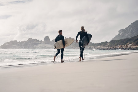 Surfing gets you active like no other hobby. a young couple out surfing together at the beach.の写真素材