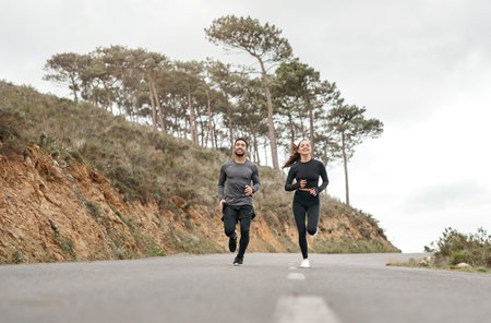 Were the dream team for fitness. Full length shot of two young athletes bonding together during a run outdoors.の写真素材