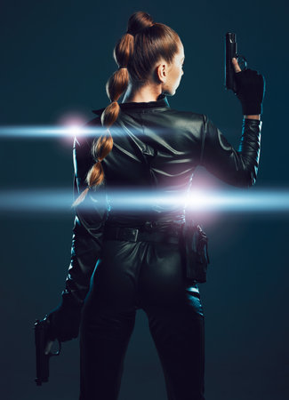 Warrior, woman and gun to fight in studio for action or danger on dark background. Strong female model, assassin or agent in scifi futuristic cosplay costume with weapon as ninja or vigilante missionの写真素材