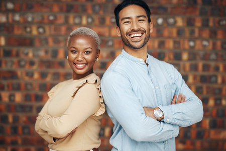 Young, professional team and partnership, portrait with teamwork and friends against wall background. Happy working together, creative pair and diversity, black woman and man, collaboration and trustの写真素材