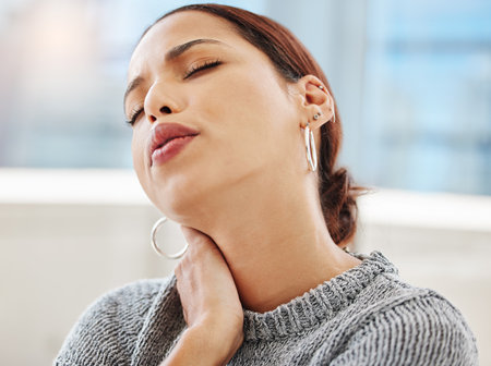 I have so much tension in my neck. an attractive young businesswoman sitting alone in her office and suffering from neck pain.の写真素材