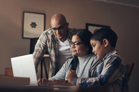 We all learnt something new in lockdown. an adorable little boy using a laptop while completing a school assignment with his parents at home.の写真素材