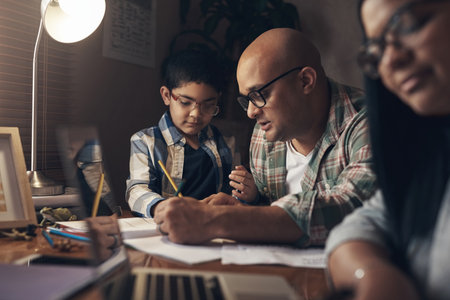 This lockdown, he added teacher to his resume. an adorable little boy completing a school assignment with his father at home.の写真素材