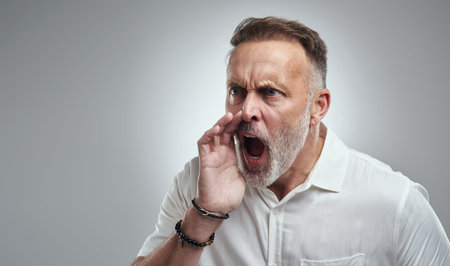 Dont make me come over there. Studio shot of a mature man yelling against a grey background.