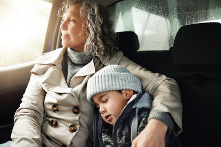 Road trip hug, sleeping child and grandma rest on travel adventure for family bonding, wellness and outdoor freedom. Sleep, driving van or relax senior woman on transport journey, holiday or vacationの写真素材