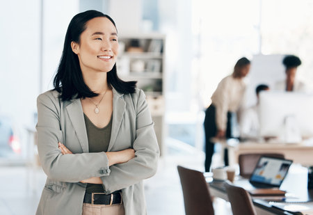 Asian, business woman with arms crossed and happy, thinking with leadership and professional mindset in workplace. Career, success and corporate female in Japanese office, happiness and confidenceの写真素材