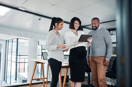 I wanted to show you how good our work looks. a diverse group of businesspeople standing together in the office and using a tablet during a discussion.の写真素材