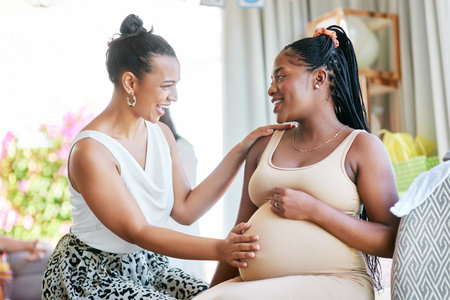Are you excited for the baby. a woman touching her friends belly during her baby shower.の写真素材