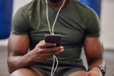 Phone, music and man hands in gym for workout, search social media and online training podcast. Closeup sports person, smartphone and listening with earphones on mobile, exercise app and connectionの写真素材