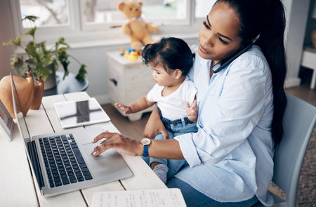 Success takes more than discipline. a young mother caring for her baby girl while working from home.の写真素材