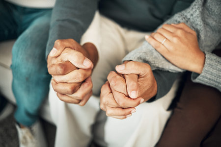 Support, love and family holding hands on sofa for comforting embrace, prayer and trust together at...