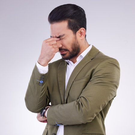 Eye pain, headache and business man in studio with anxiety, debt or worry of stock market crash. Corporate male, model and migraine of stress, bankruptcy and burnout of financial crisis in depressionの写真素材