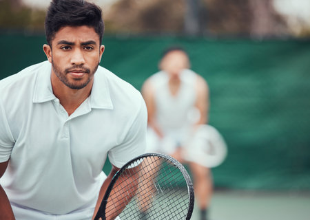 Two ethnic tennis players holding rackets and ready to play court game. Serious, focused athletes...