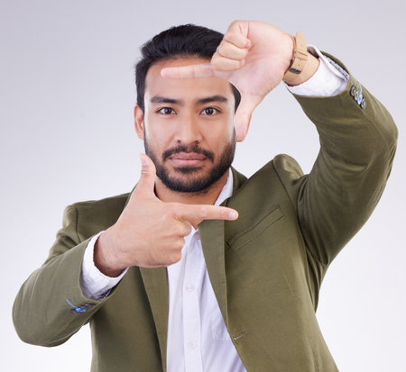 Finger framing, portrait and business man in studio, background or capture profile picture. Face of male model, hands and frame perspective for selfie, photography ideas or imagine border of planningの写真素材