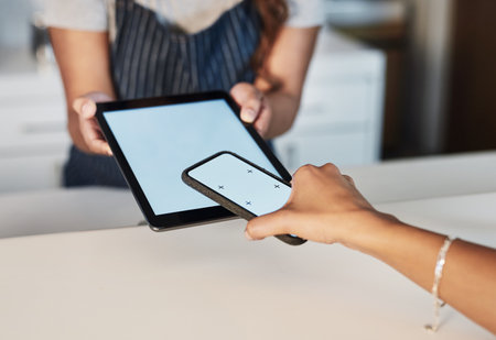 Digital pay-point portals make things a lot easier. Closeup shot of a digital payment being made with a cellphone and digital tablet in a cafe.の写真素材