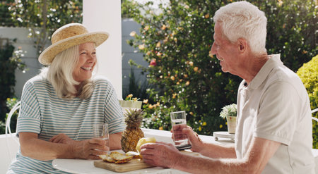 We got to retire together. a happy senior couple sitting outside together and enjoying a snack.の写真素材