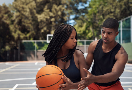 Gaining strength, coordination and muscular endurance. two sporty young people playing basketball on a sports court.の写真素材