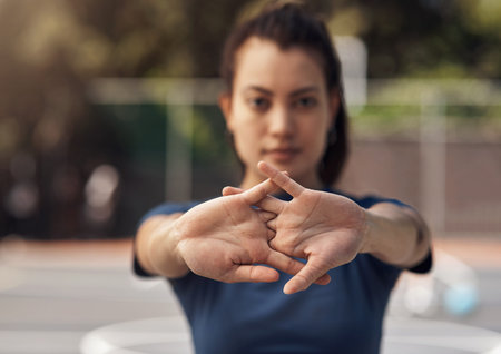 Lets get this game started, shall we. Portrait of a sporty young woman stretching her arms on a...