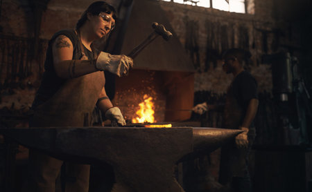 Metal is just metal until a blacksmith comes along. a young woman hitting a hot metal rod with a...