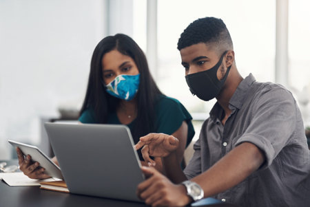 They wont let the pandemic set them back. two businesspeople working together on a laptop in an office.の写真素材