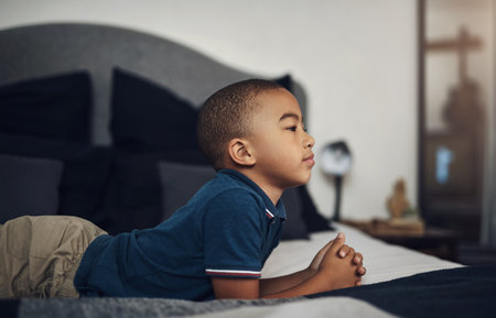 What can I do for fun. an adorable little boy lying on his bed at home.の写真素材