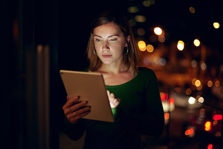 Her dedication will allow her to reach every height of success. a businesswoman using a digital tablet in an office at night.の写真素材