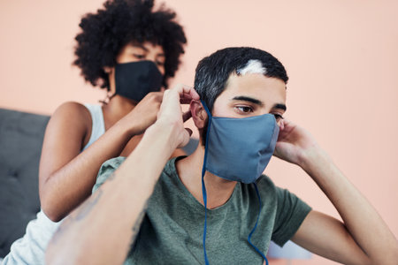 Were fighting coronavirus together. a woman helping her boyfriend with his mask.の写真素材