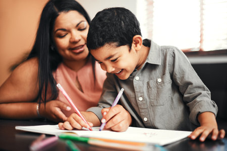 Getting creative during playtime. an adorable little boy colouring in with his mother at home.の写真素材
