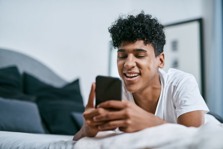Just letting you know Im thinking of you. a young man relaxing on his bed and using a smartphone.の写真素材