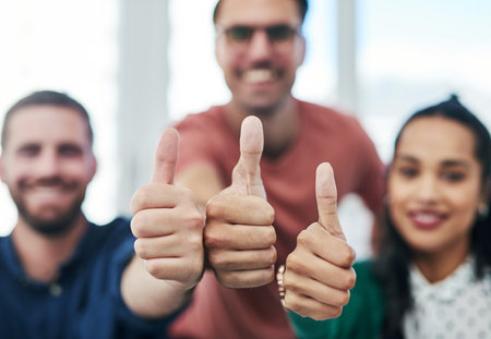 Nothing helps you realise your full potential like positive reinforcement. Portrait of a group of young businesspeople showing thumbs in a modern office.の写真素材