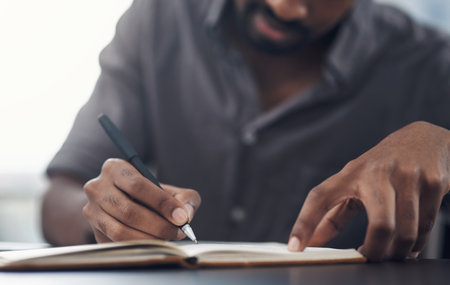Planning out the work week in his diary. Closeup shot of an unrecognisable businessman writing in a notebook in an office.の写真素材