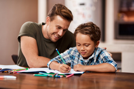 He makes me a very proud father. a man sitting with his son while he does his homework.の写真素材