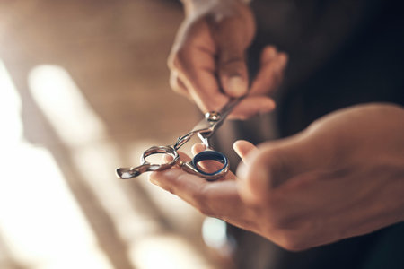 Dont thank me, thank the scissors. an unrecognisable barber standing and holding a pair of shears in his salon.の写真素材