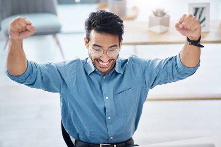 Winner, success and happy businessman in office, celebrating and excited for email, review or loan approval. Hands, celebration and corporate male online winner with emoji, wow or winning gestureの写真素材