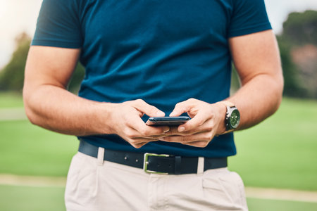 Man, hands and phone texting in communication on golf course for sports, social media or networking outdoors. Hand of sporty male chatting on smartphone or mobile app for golfing research or browsingの写真素材