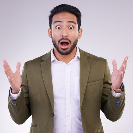 Wow, shock and surprise, portrait of Indian man with hands up and shocked by amazing news or deal announcement in studio. Businessman with surprised face, emoji or meme isolated on white background.の写真素材