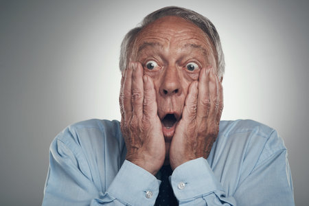 Oh Its game over. a senior businessman standing against a grey studio background with his face in...