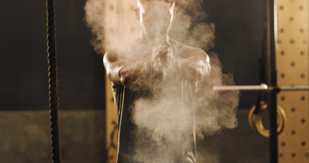 Im ready to begin now. a muscular young man clapping his hands dusted with sports chalk in a gym.の写真素材