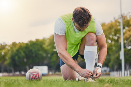 Sports, soccer and man tie shoelace, training and workout for balance, wellness and healthy lifestyle. Male player, guy or athlete tying shoe, fitness and practice for match, exercise and performanceの写真素材