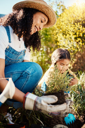 Family, kids or gardening with a mother and daughter planting plants in the backyard together. Nature, children or landscaping with a woman and female child working in the garden during springの写真素材