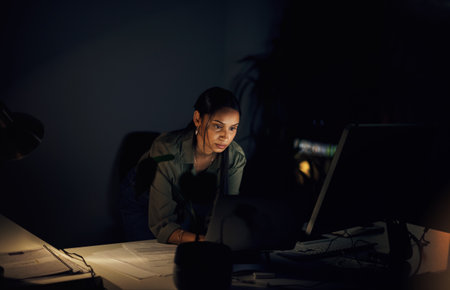 Nothing will shatter her focus. a young businesswoman working on a laptop in an office at night.の写真素材